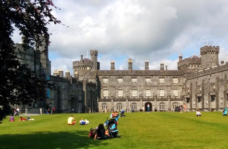 Vue sur un château avec des personnes installées sur la pelouse devant