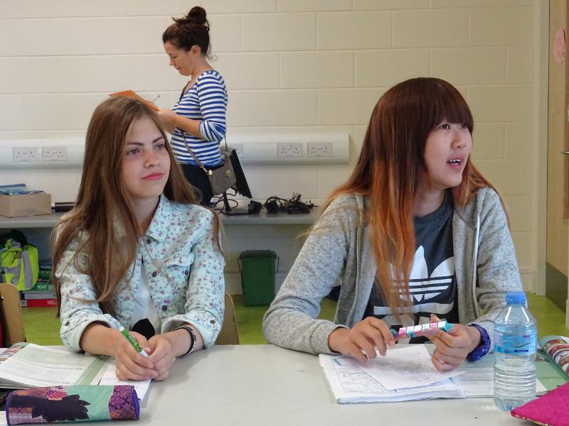 deux jeunes filles avec leurs cahiers assises à une table d'école