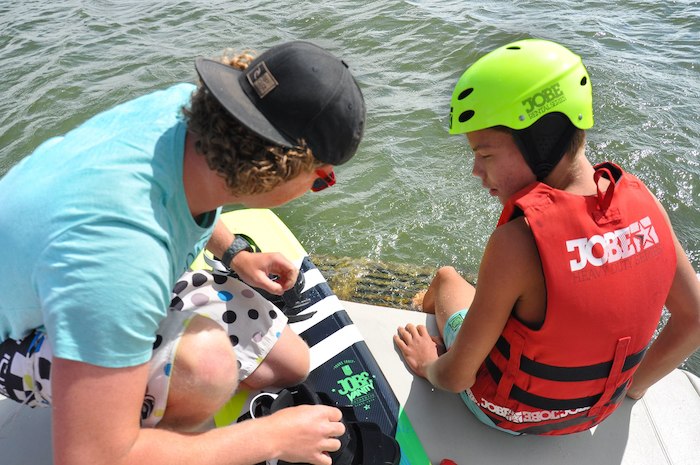 moniteur qui montre la planche à un jeune en colonie de vacances wakeboard