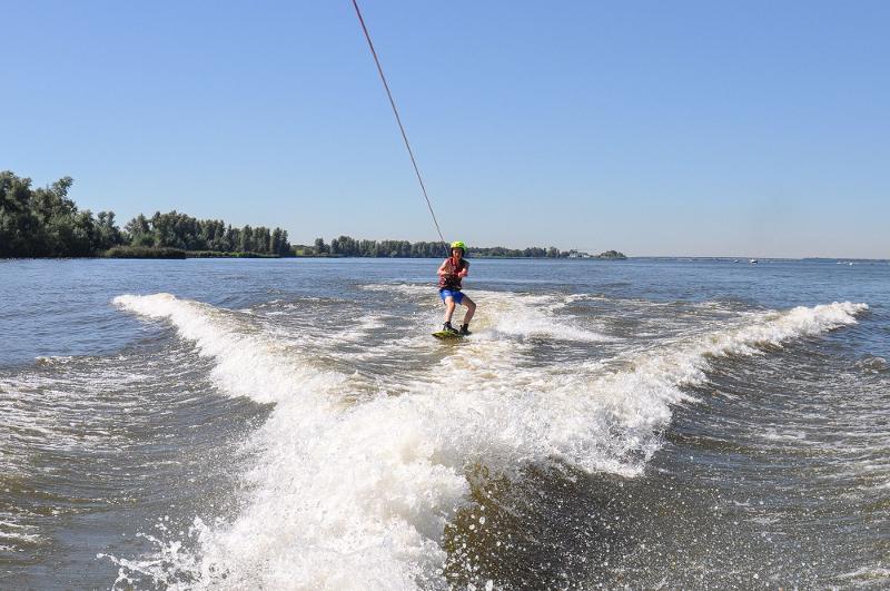 jeune sur sa planche entre les vagues en colo wakeboard