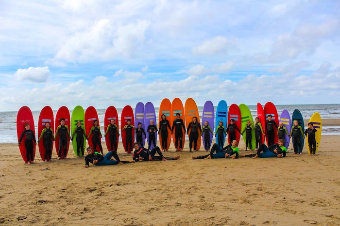 Photo de groupe sur la plage avec leurs planches de surf colorées