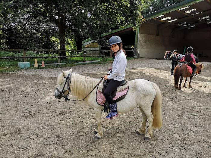 Une fille est à dos de poney dans la carrière lors d'une colonie de vacances bretagne