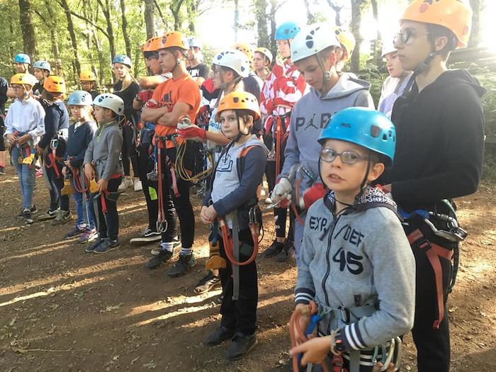 Les ado sont équipés et suivent les consignes de sécurité face à l'instructeur de l'accrobranche lors d'un camp de vacances
