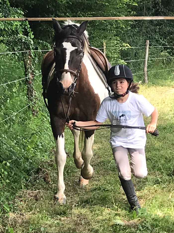 Un enfant promenant son cheval pendant une colonie de vacances équitation