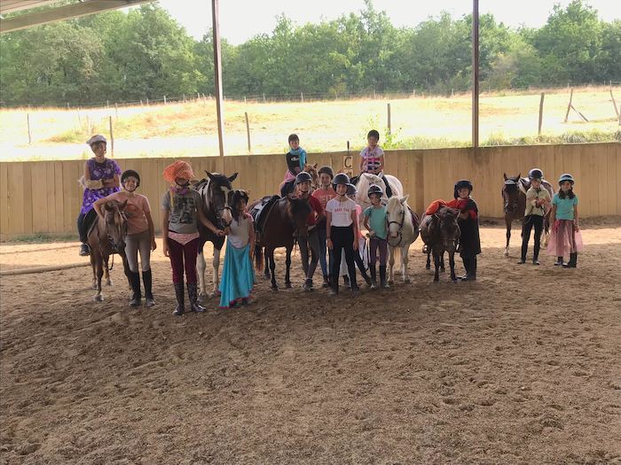 plusieurs enfants dans un manège avec les chevaux