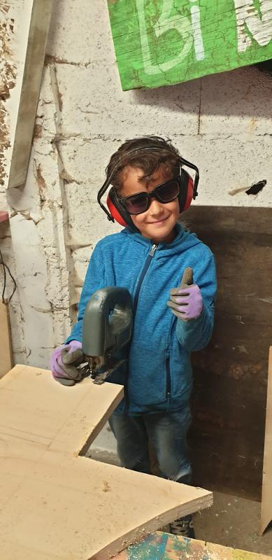 Enfant faisant de la ponceuse pendant une colonie de vacances bricolage