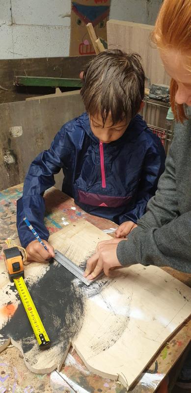 Un enfant faisant des mesures pendant une colonie de vacances bricolage