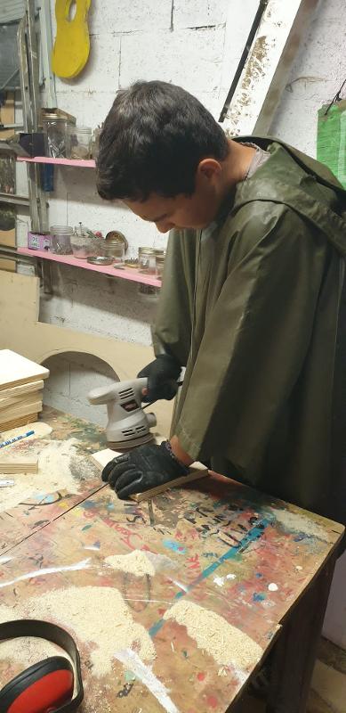 Un homme faisant du ponçage pendant une colonie de vacances bricolage