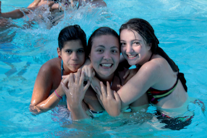 Trois jeunes filles nagent dans la piscine de leur colonie de vacances