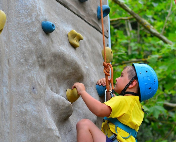 Jeune garçon s'attaque à l'escalade de façon concentrée