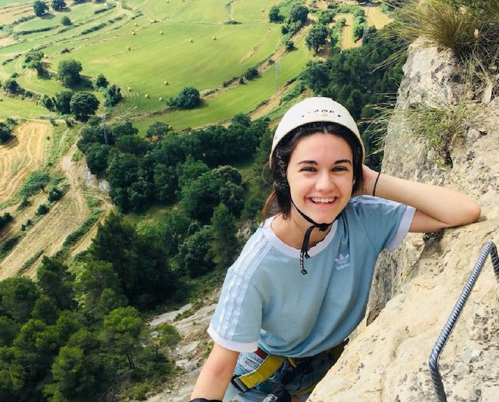 Appuyée contre un rocher, une jeune fille sourit en colonie de vacances nature