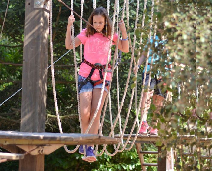 Une jeune fille concentrée fait de l'accrobranche