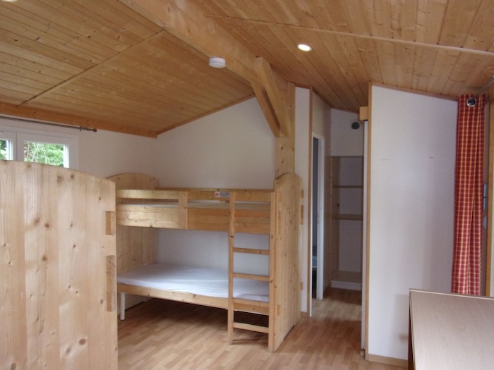 Vue de l'intérieur des chalets en bois avec lits superposés lors de la  colonie de vacances haute garonne