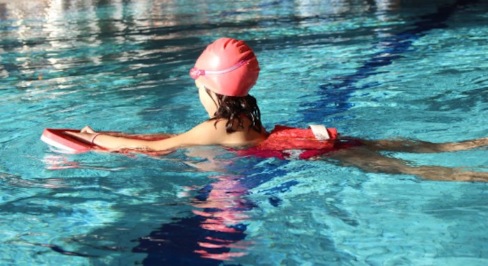 Fille apprenant a nager dans la piscine en colo de vacances pas cher
