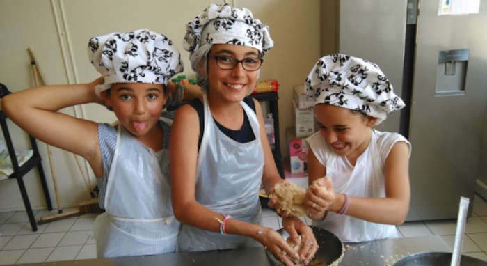 Enfants qui rigolent lors d'un atelier culinaire en colo