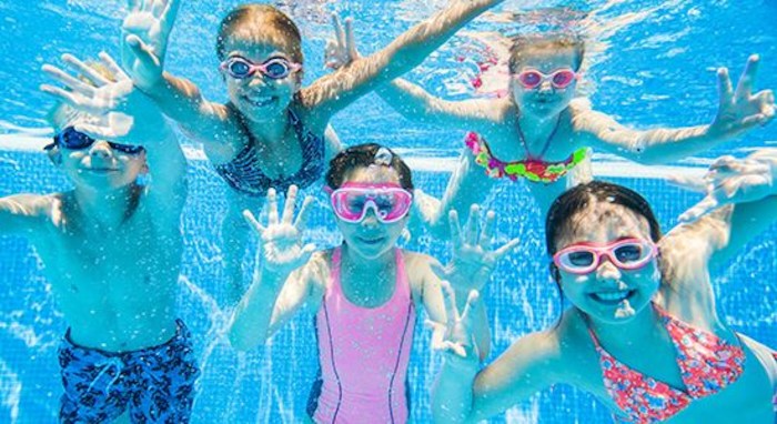 Les jeunes sont sous l'eau dans la piscine lors d'une colonie de vacances artistique