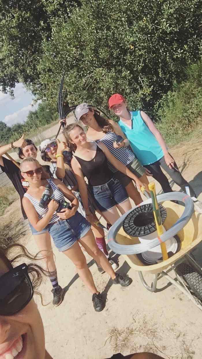 Les jeunes tiennent une brouette et des outils pour mener a bien leurs travaux lors d'une colo bordeaux
