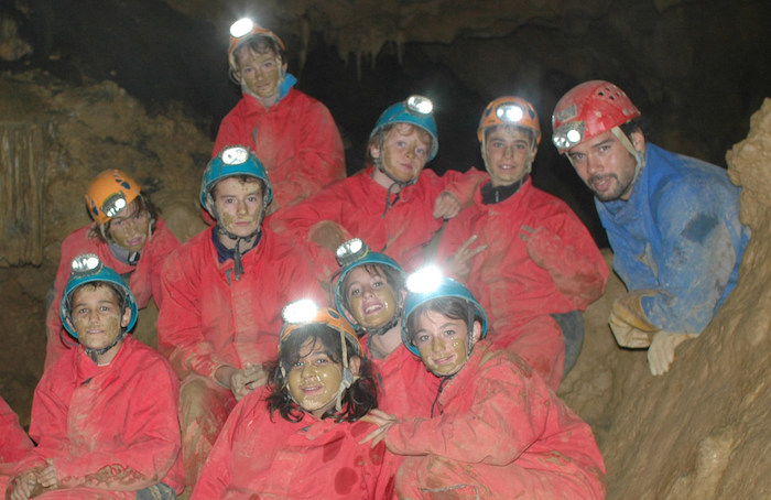 Un groupe de jeune en tenue de spéléologie dans une grotte lors d'une colonie de vacances en Hautes-Pyrénées