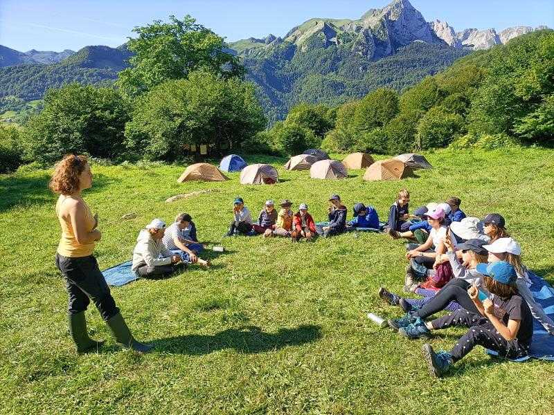 Les enfants de la colonie de vacances sont assis dans l'herbe à côté de leur campement