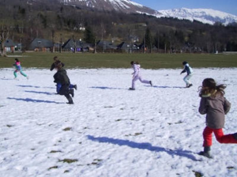 Les enfants de la colonie de vacances dans les Pyrénées courent dans la neige