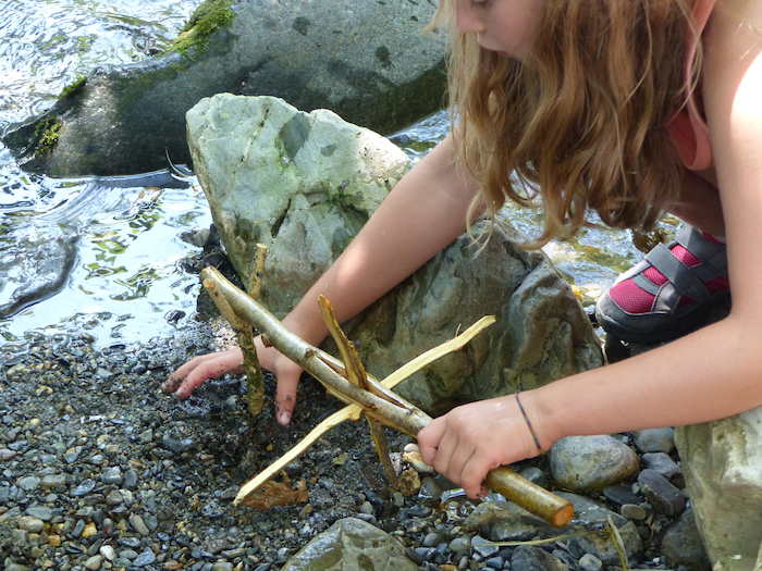 Une fille bricole près de la rivière lors d'une colonie de vacances d'éducation à l'environnement