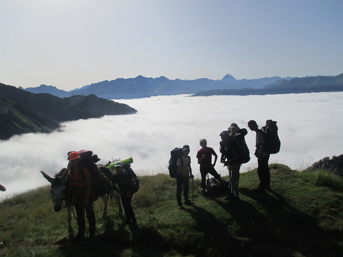 Les jeunes de la colonie de vacances dans les Pyrénées sont debout en haute de la montagne avec une mer de nuage en arrière plan