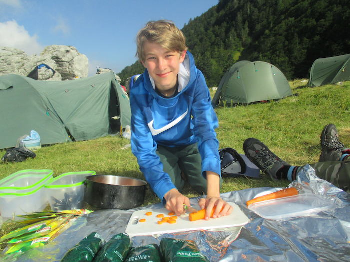 un enfant coupe des carottes au milieu du campement lors d'une colonie de vacance nature dans les Pyrénées