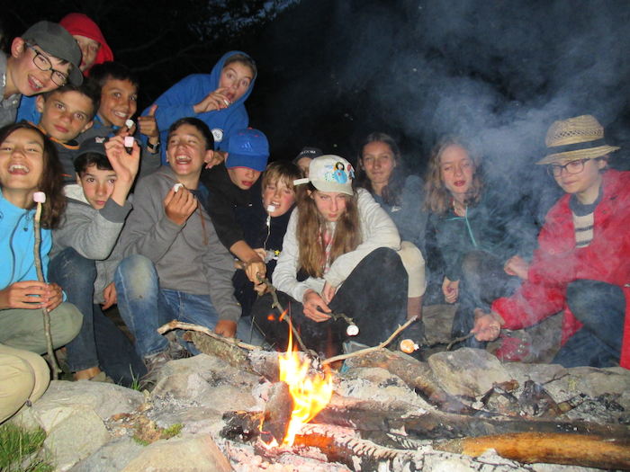 Les jeunes se retrouvent autour du feu de camp  lors d'une colonie de vacances nature dans les Pyrénées