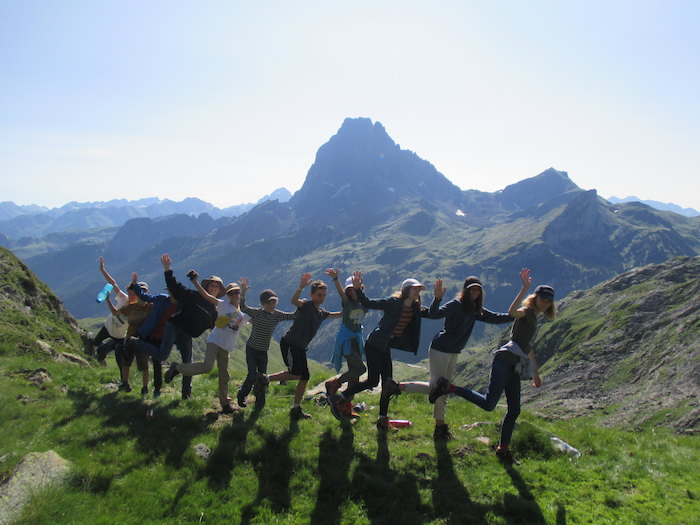 Les jeunes se tiennent la main et sont alignés devant les montagnes.