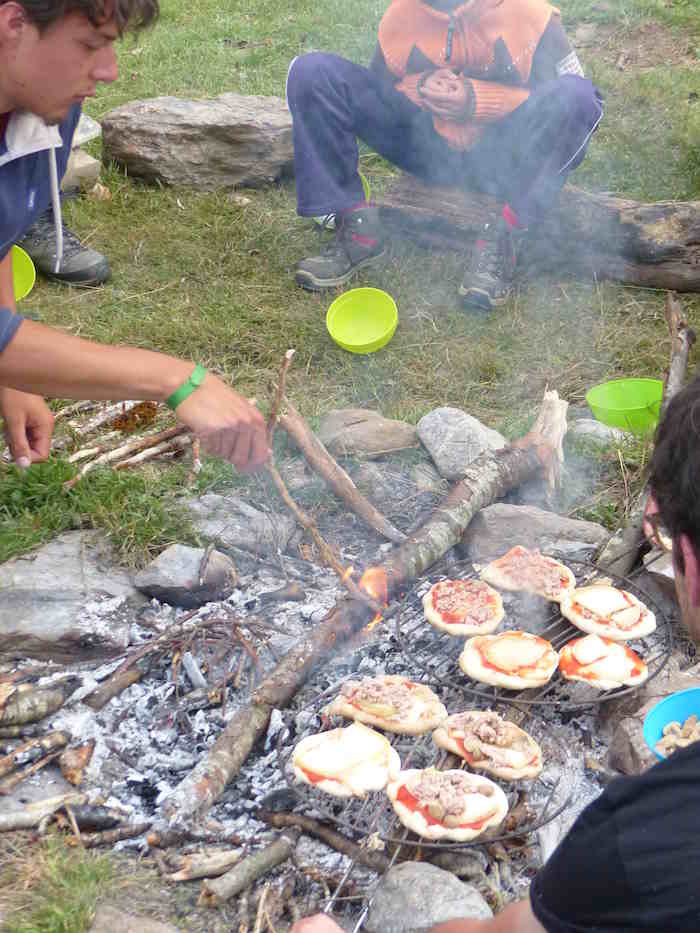 Cuisson des pizzas dans le feu de camp  lors d'une colonie de vacances dans les Pyrénées.