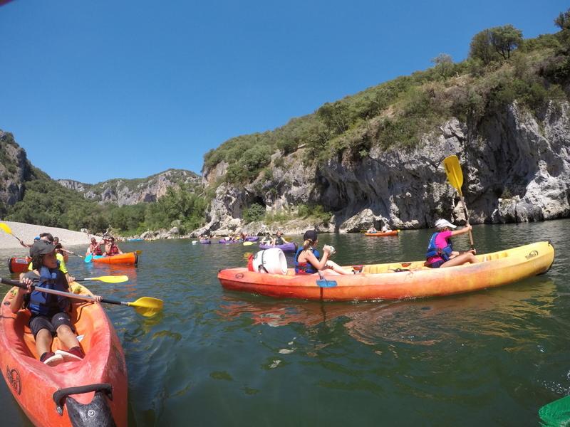 plusieurs enfants sur des kayaks qui s'amusent dans une rivière