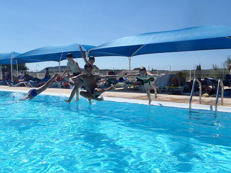 enfants qui regardent l'appareil photo en sautant dans la piscine 