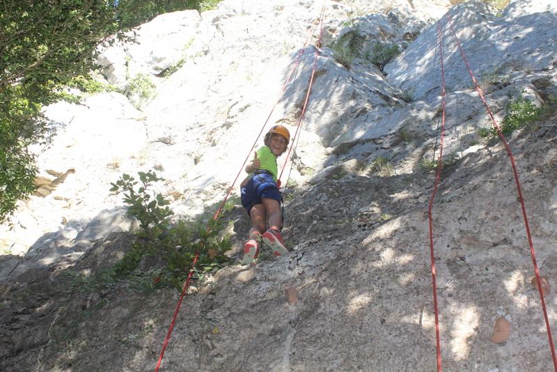 Un enfant escaladant une falaise pendant une colonie de vacances Occitanie