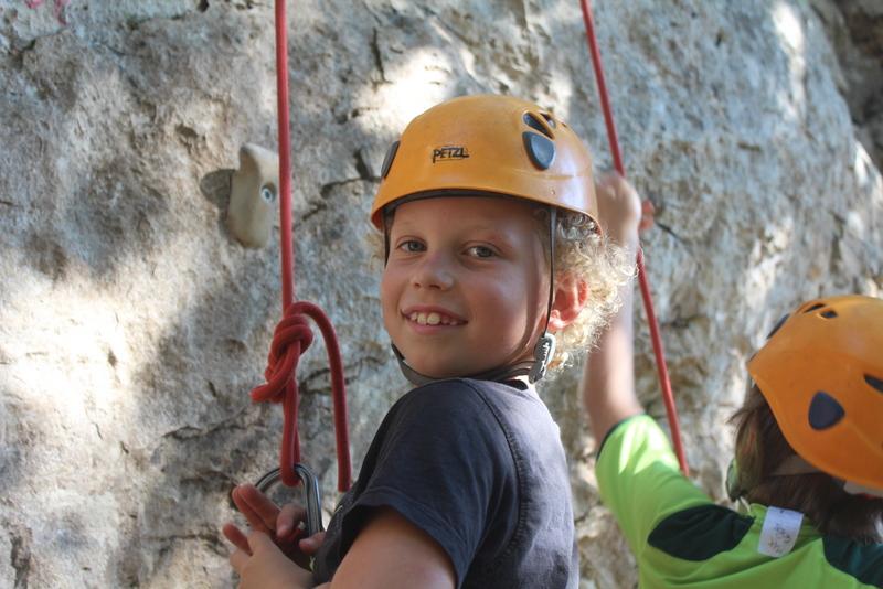 Enfant faisant de l'escalade pendant une colonie de vacances Occitanie