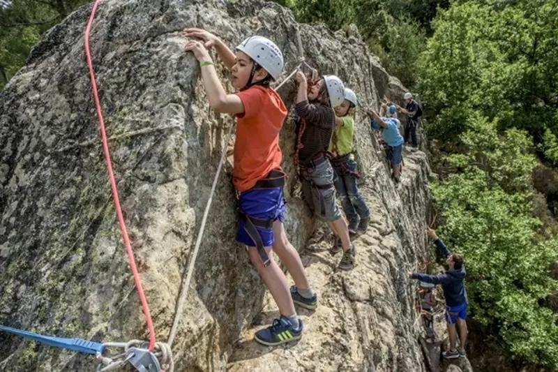 Des jeunes font de l'escalade sur une paroi rocheuse une en colonie de vacances occitanie 