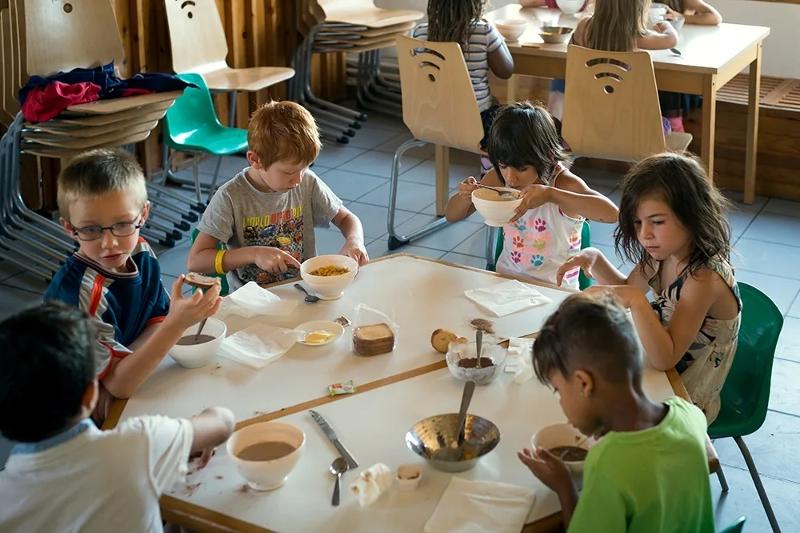 Un groupe d'enfants prend le petit déjeuner en colonie de vacances Occitanie