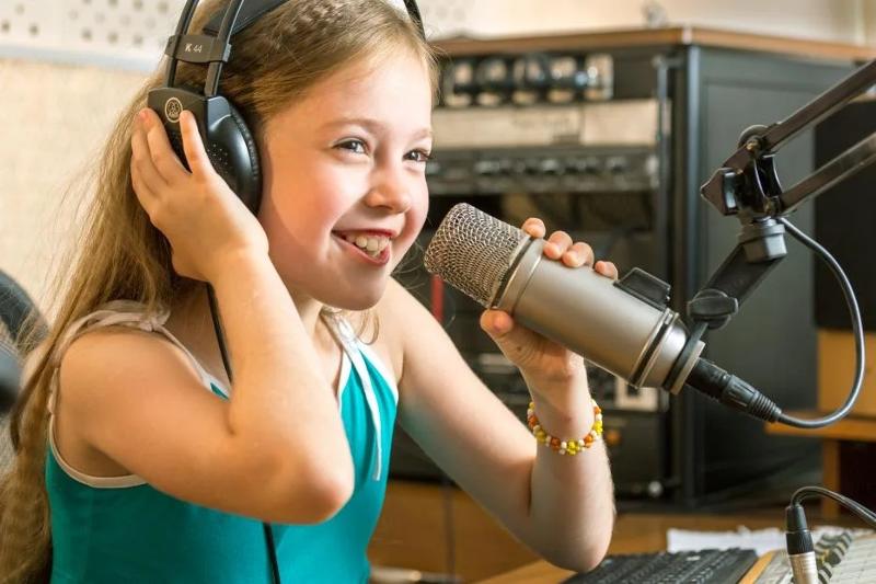 Une fille chante dans un micro en colonie de vacances Occitanie