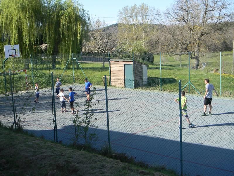 Des jeunes de la colonie de vacances jouent au basket sur un terrain en extérieur