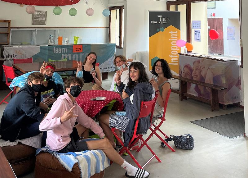 Jeunes dans une salle assis qui sourient et font un signe avec la main en séjour à l'étranger