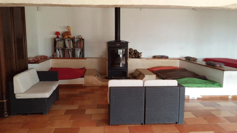 Salle de détente de la colonie de vacance à Lauzerte avec canapés, coussins et poêle