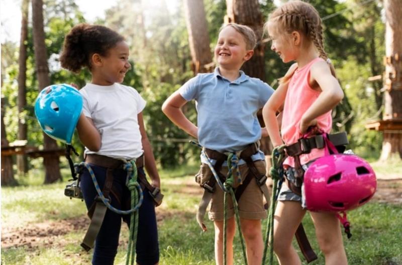 Trois enfants en baudrier se prépare à grimper dans le parc accrobranche durant la colonie de vacances Tarn-et-Garonne