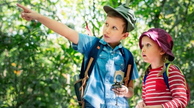 Un garçon avec une boussole indique la direction à suivre à une fillette en colonie de vacances Tarn-et-Garonne