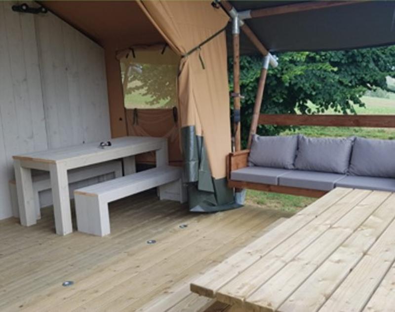 Terrasse en bois de la colonie de vacances Tarn-et-Garonne avec chaise à bascule et table de pique-nique couverte