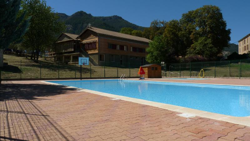 grande piscine en centre de vacances en pleine nature sous un ciel bleu