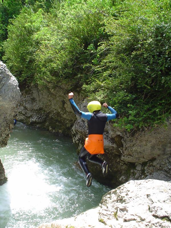enfant qui saute dans une rivière avec des protections sur lui