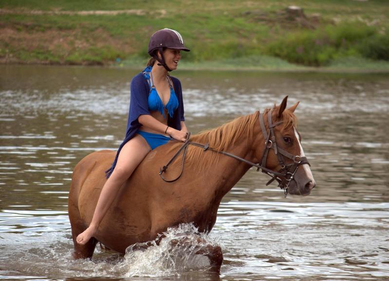 Une ado monte son cheval à cru dans une rivière 