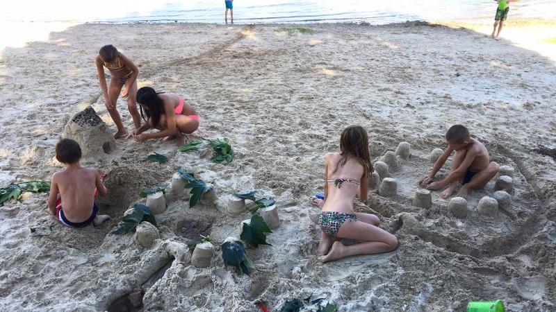 Les enfants de la colonie de vacances équitation construisent des chateaux de sables sur la plage 