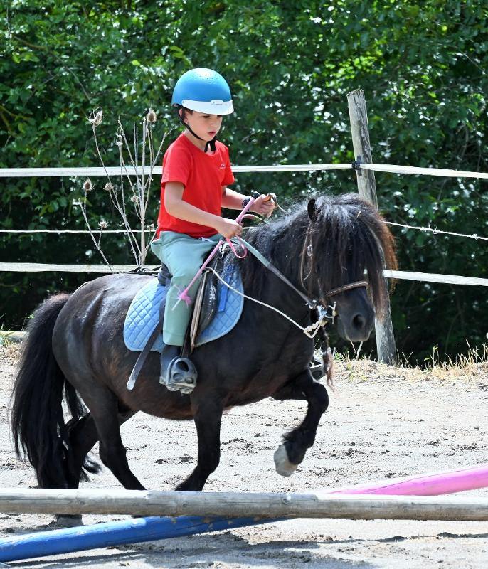 Un enfant et son poney saute un obstacle en colonie de vacance passage gallop 