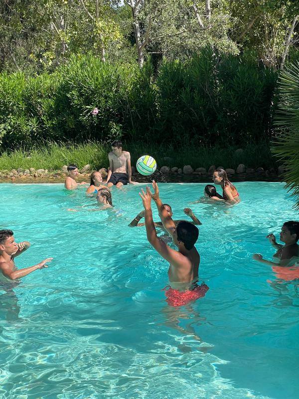 Enfants dans une piscine qui jouent au ballon au soleil en séjour linguistique Italie ado