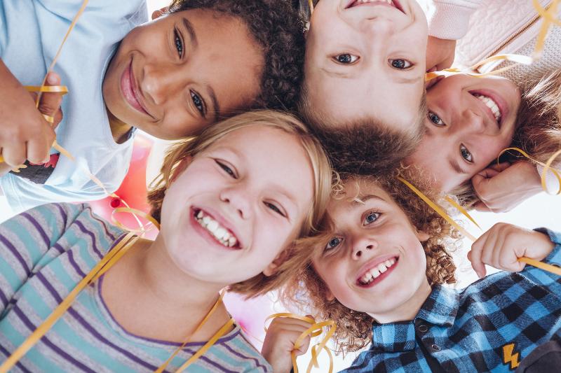 Des enfants la tête baissée qui regarde la caméra en souriant 